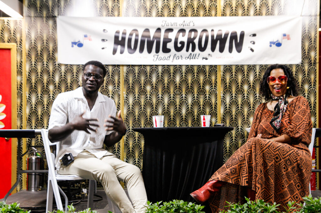 a man and a woman seated on-stage with a HOMEGROWN banner behind them